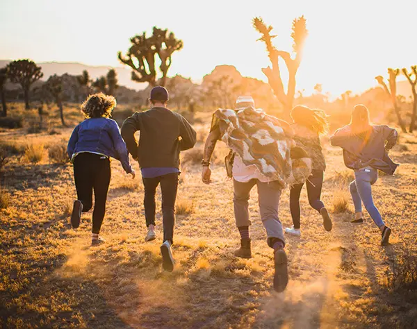 Group of young adults running towards horizon on a sunny day